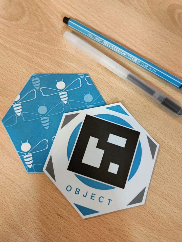 Printable Hachi learning card with an AR marker, on a desk.