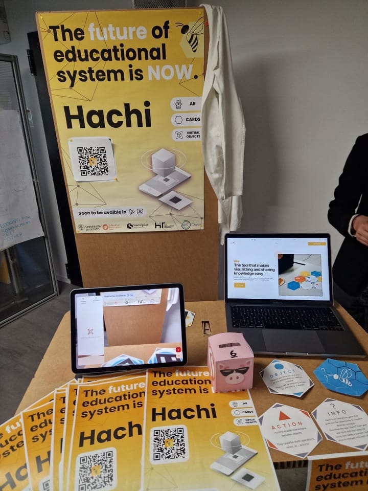 Hachi stand with posters, printed cards and the app running on a tablet.